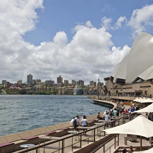 Closeup of restaurant umbrellas and famous Sydney Opera House in harbour in New South