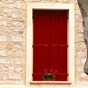 Dark red shutters in the wall of a house in France