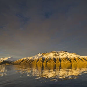 Greenland. Kong Oscar Fjord. Deeply eroded mountains reflected in the calm water