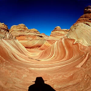 Hiker in the Wind and water eroded Navajo sandstone in Coyote Buttes North, Paria