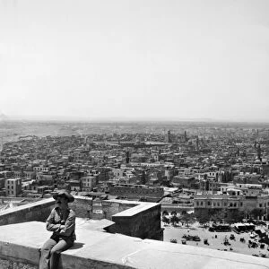 EGYPT: CAIRO. A view of the city from the Citadel with a man seated on the wall in the foreground