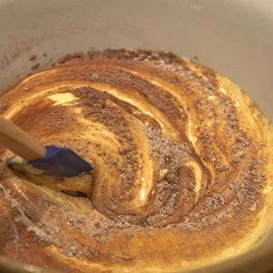 Folding sifted flour and cocoa into mixture of eggs and sugar
