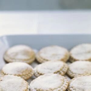 Mince pies dusted with icing sugar on baking tray, close-up