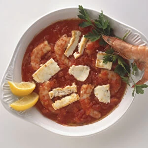 Overhead view of Garides giouvetsi, a modern dish of large shrimps or prawns baked in a tomato, olive oil and parsley sauce and topped with feta cheese, served in a white dish