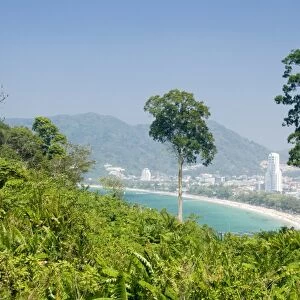 Thailand, Phuket, Ao Patong, tourist resort seen from lush hill with mountains in distance