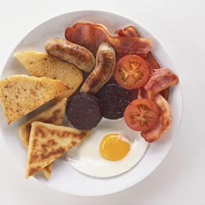 Ulster Fry, breakfast plate including sausages, bacon, black pudding, fried egg, tomatoes and bread, view from above