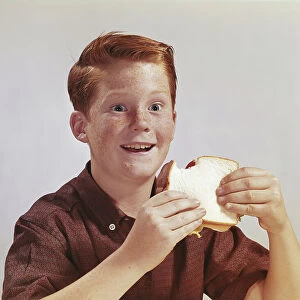 Boy eating sandwich, smiling