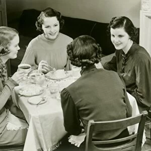 Four women sitting at table, drinking tea and chatting