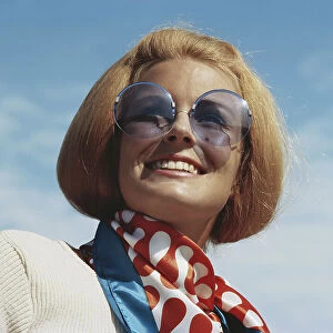 Young woman wearing sunglasses, smiling, close-up
