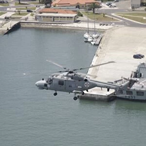 A Portuguese Navy Lynx helicopter flying over the harbor