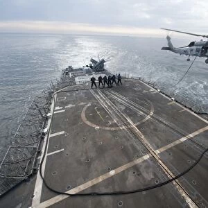 Sailors hold a fuel line during a helicopter-in-flight refueling exercise