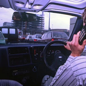 Man driving whilst using built-in car telephone 1990. Creator: Unknown