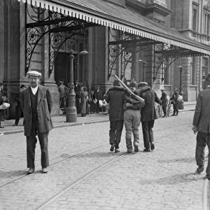 Two civilians help a wounded Belgian soldier to the railway station at Louvain