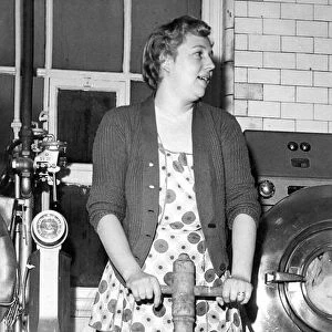 Mrs. Hedley demonstrates the old post-tub method of washing clothes, in February 1960