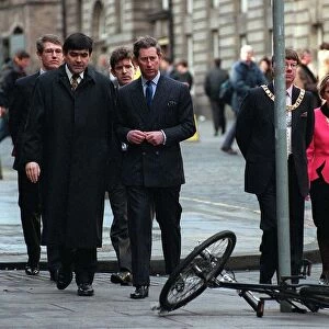 Prince Charles walking in the High Street Edinburgh about to pass bicycle on ground