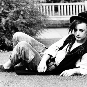 Singer Boy George lying on the grass in his garden. 28th September 1982