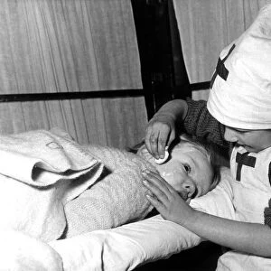 Three year old Brenda Aukett being checked over by nurse Janice Garry, aged 5